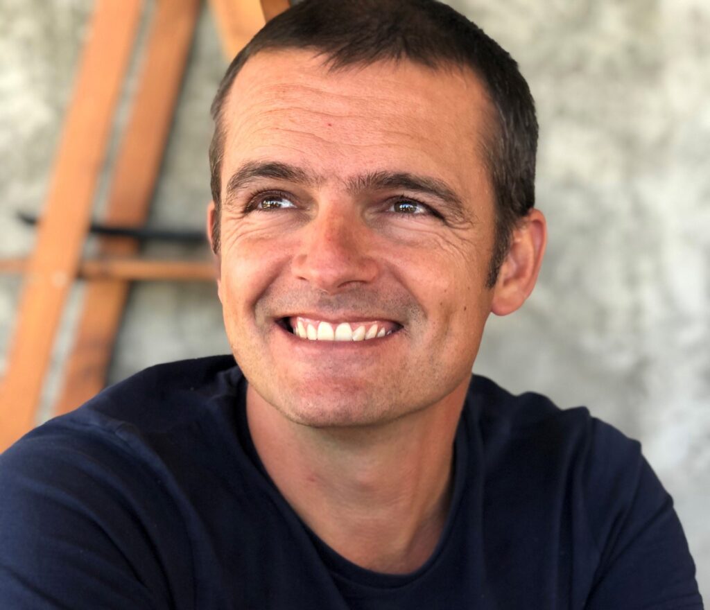 Laurent Berguerand, souriant, les bras croisés sur une table.